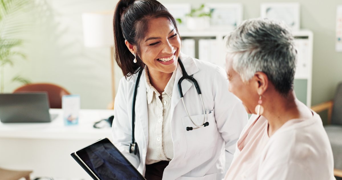 A clinician speaks with an older patient during an office visit.