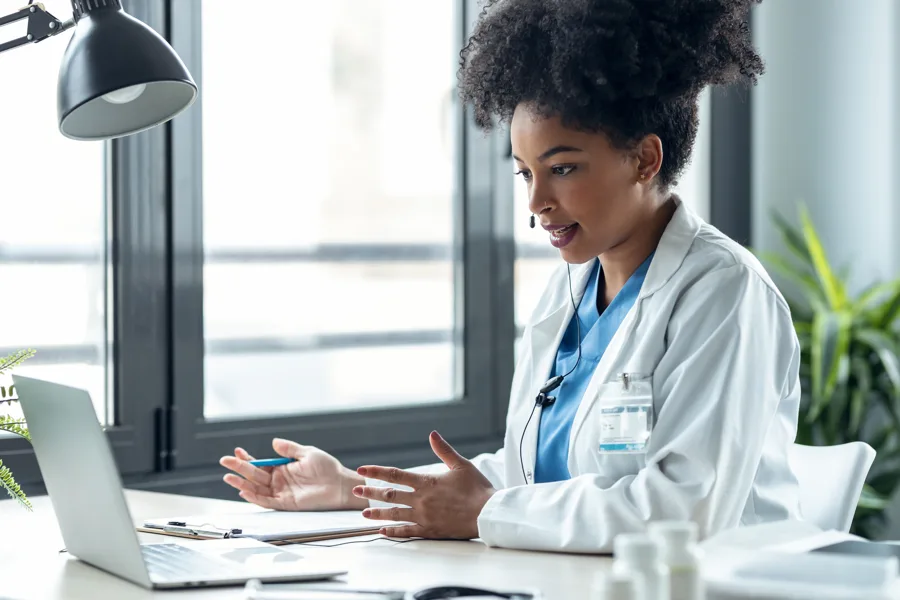 A clinician using a laptop and headset for a video conversation