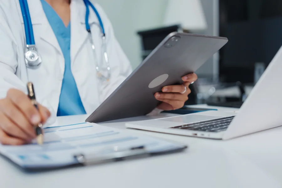 Clinician reviewing paperwork beside a laptop